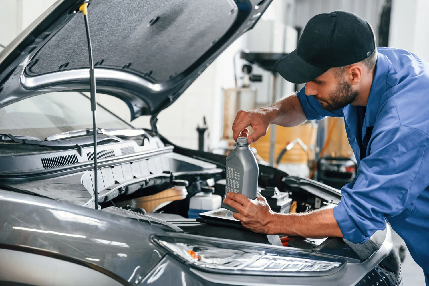 engineer refueling and pouring oil into the engine of the car.
