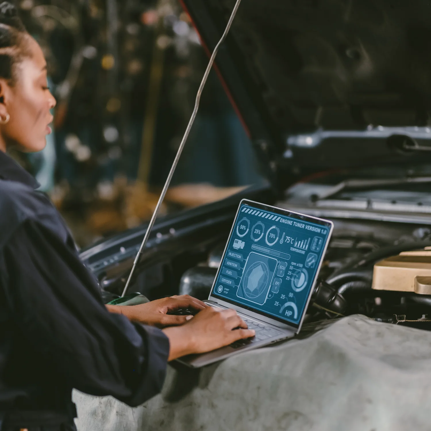 woman typing on laptop computer in front of car engine