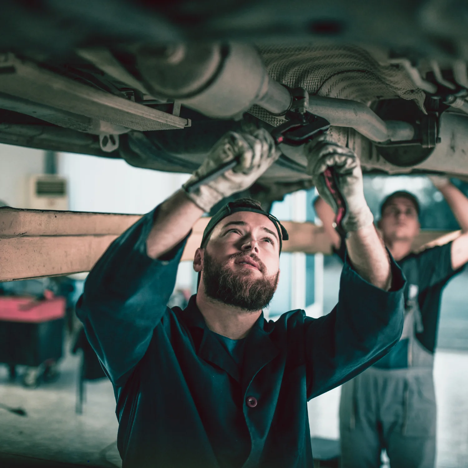 engineer with green suit replacing car exhaust in tire shop