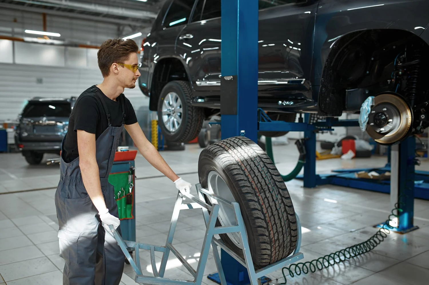mechanic man fixes problem with wheel in mechanical workshop